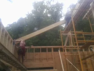 Carpenter raising a rafter beam on a new second story frame in Mulberry