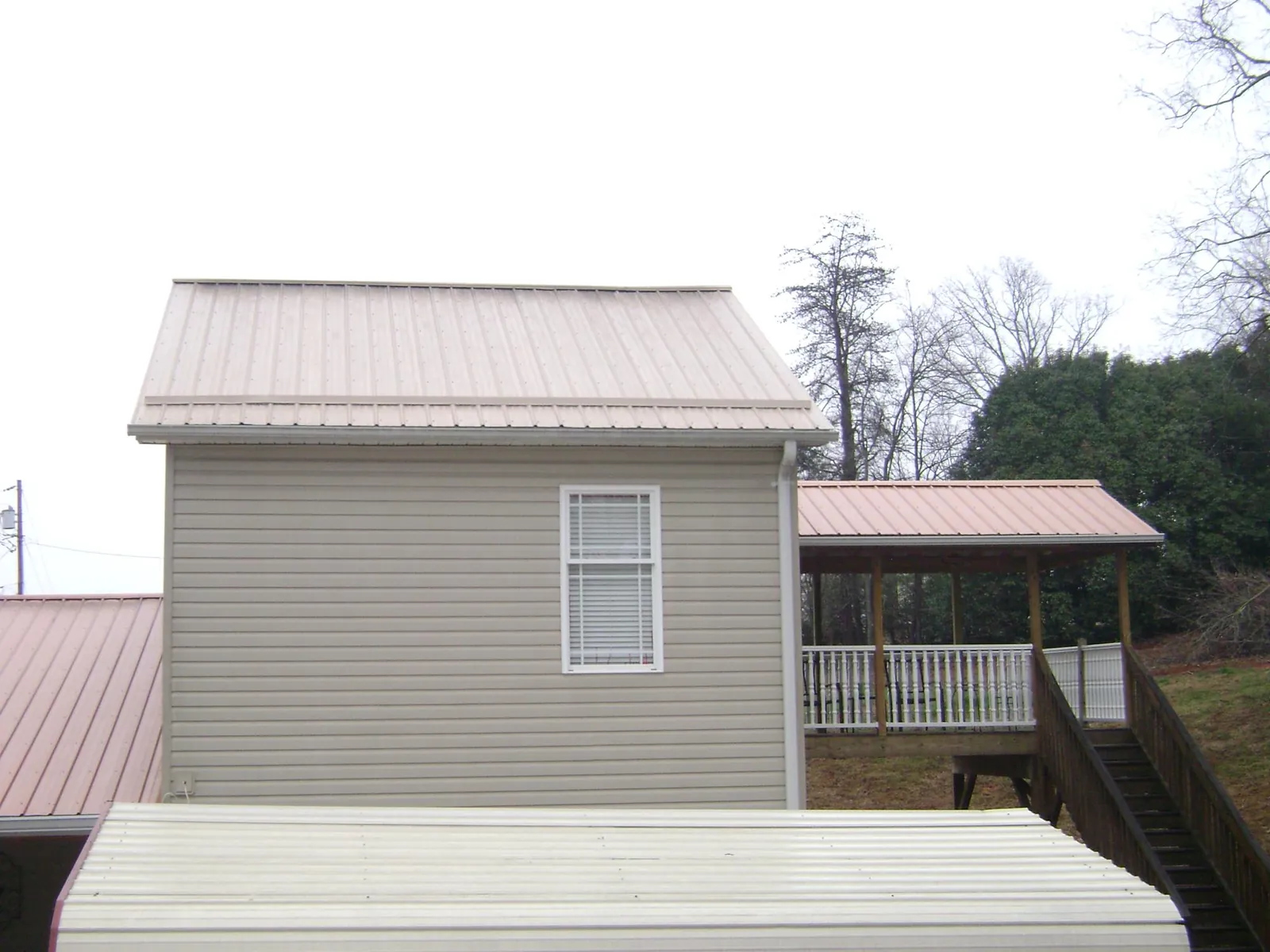 Tan metal roofs on a two story addition and attached porch, from a Roof Replacement job in Mulberry